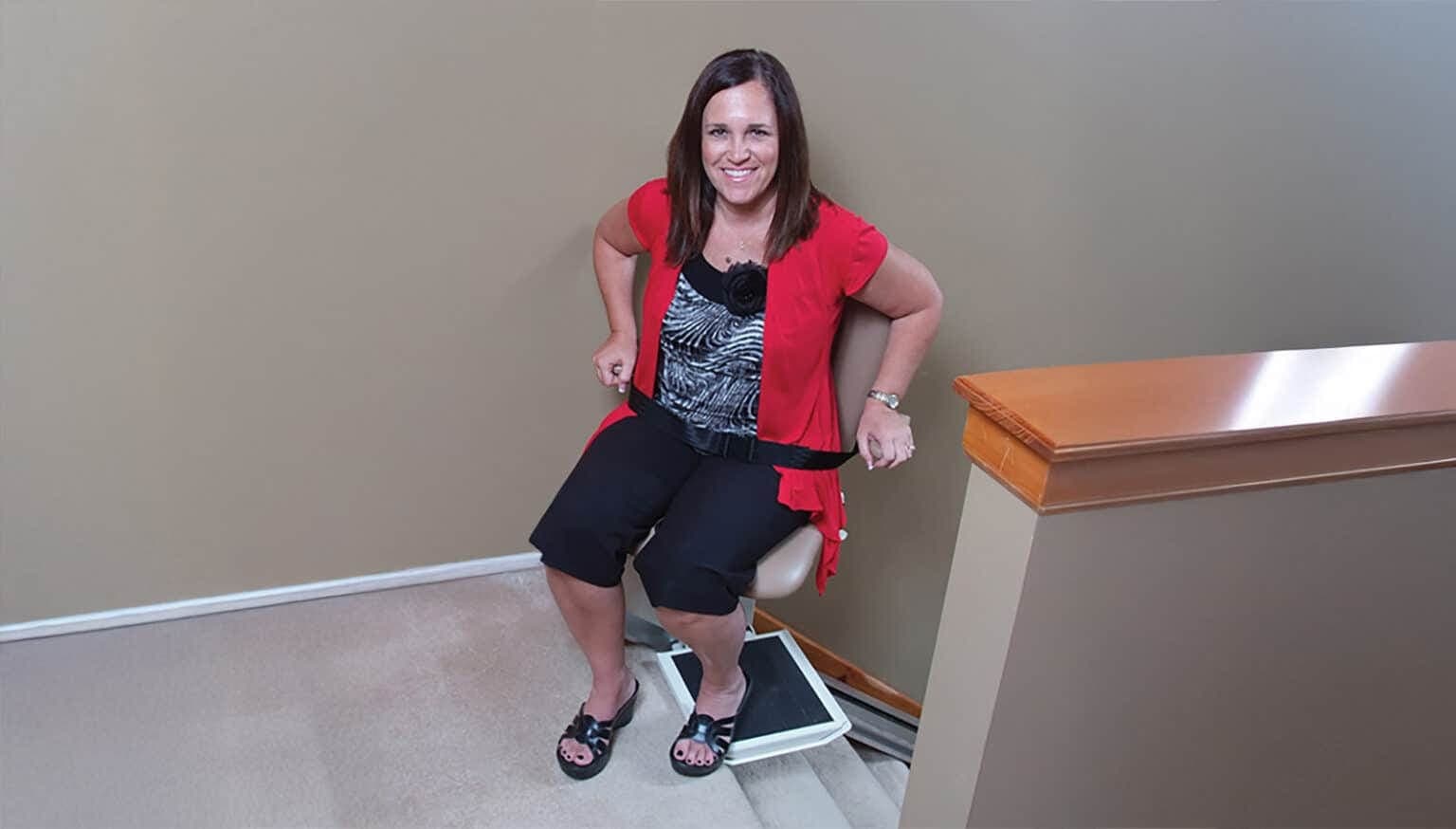Homeowner seated on a stair chair at the top of her stairs
